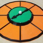 A photo of a brightly coloured game spinner featuring a tray around the outside which can hold game pieces.