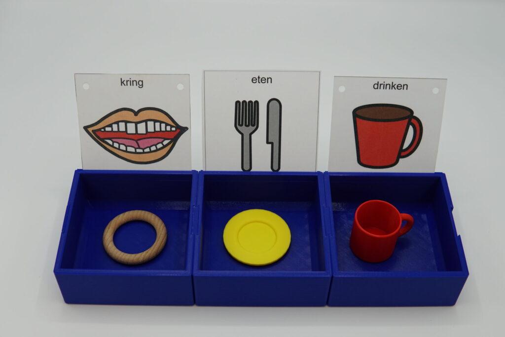 three trays interlocking and each holding objects of reference. cards with symbols are place in trays